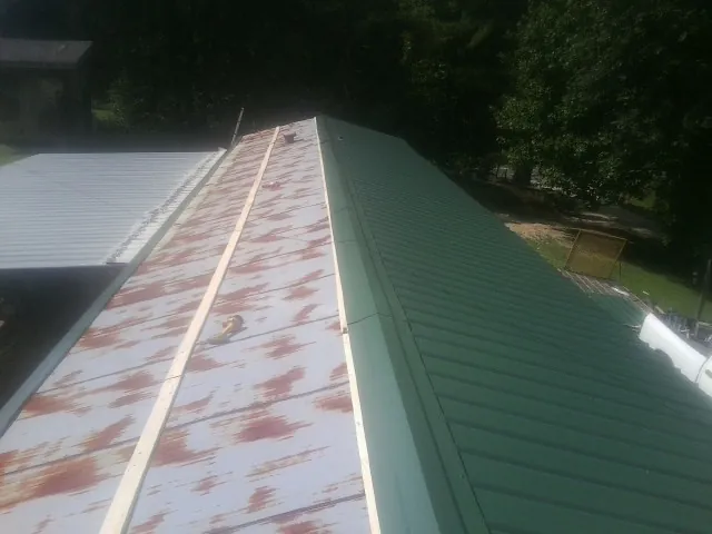 Old rusted panels beside newly installed green metal roofing — Wind Damage Roof Repair by Roofing Brothers in Courtland