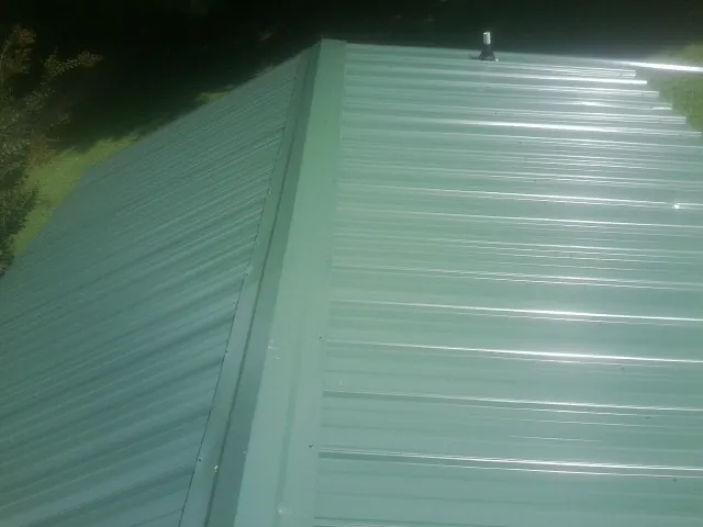 New green metal panels meeting at the ridge of a roof — Flat Roof Repair work by our crew in Courtland
