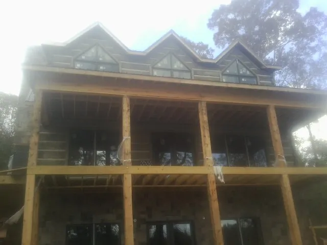 Dormers and porch framing on a large log home under construction — Roof Coating work by our crew in Courtland